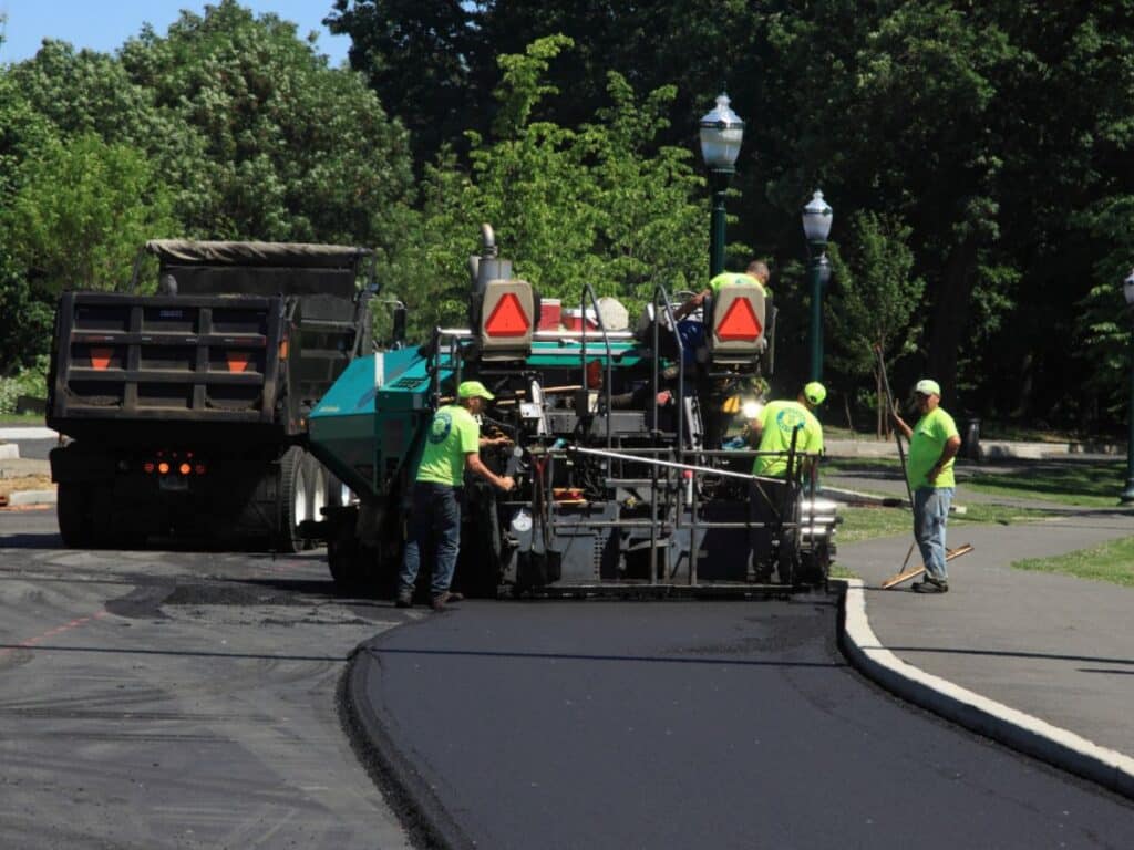 workers with paver machine sealing the road with asphalt